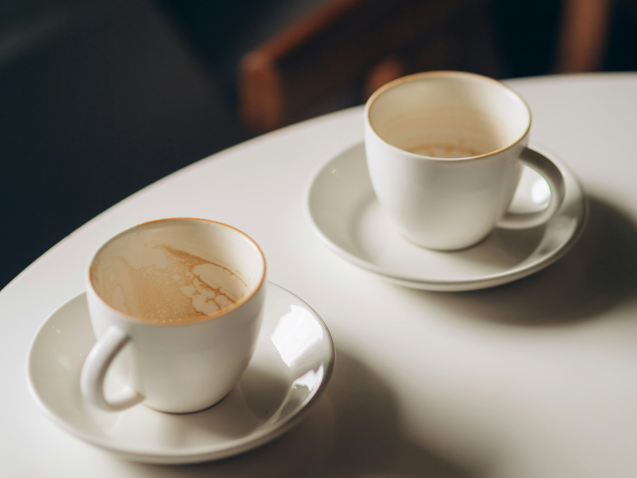 Two empty coffee cups on saucers, sitting apart on a table, representing the gap between what you were taught and what your body needs.